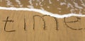 Handwriting word Time written in the sand.