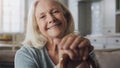 Time hasnt and never will steal my smile. a senior woman sitting alone on the sofa at home and holding her walking stick