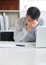 Time for a holiday...an exhausted-looking businessman sitting in front of his laptop at his desk.