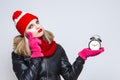 Time Ideas. Portrait of Thinking Caucasian Girl In Warm Hat and Scarf Posing With Mournful Expression. Holding Round Clock On Hand