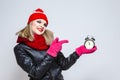 Time Ideas. Portrait of Thinking Caucasian Girl In Warm Hat and Scarf Posing With Winning Smile. Holding Round Clock On Hand