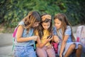 Three school little girls using smart phone together