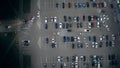 A time-lapse car traffic on a big parking lot near the supermarket at night.