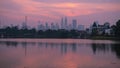 Time lapse: Kuala Lumpur city skyline during sunset overlooking a lake.