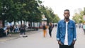 Time-lapse of lonely African American guy student standing in pedestrian street in big city with hands in pockets and