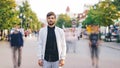 Time-lapse portrait of lonely man from big city standing in street alone and looking at camera while bypassers are