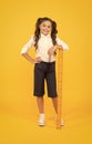 Time for learning. Small school child with ruler learning maths and geometry on yellow background. Little girl learning