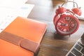 Time management concept, Alarm clock,notebooke and computer laptop on wooden table in office.