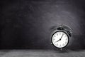 Retro black alarm clock alerting at seven o`clock on chalkboard background. Royalty Free Stock Photo