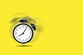 Retro black alarm clock alerting at seven o`clock on yellow background. Royalty Free Stock Photo