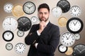 Time management concept. Thoughtful businessman surrounded by different clocks on color background