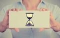 Time management concept. Woman hands card with sand clock sign