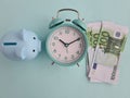 Time management and financial success with 100 euro banknote with alarm clock with piggy bank Royalty Free Stock Photo