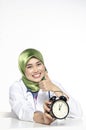 Time management and punctuality concept, young medical staff holding alarm clock over white background