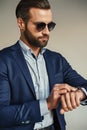 Time is money...Busy handsome businessman in stylish suit and sunglasses is checking time while waiting for partner.