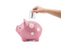 Time and money - hand putting a clock into a pink piggy bank