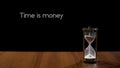 Time is money, wise phrase against black background, sand flowing in hourglass Royalty Free Stock Photo