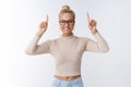 Time move forward. Portrait of attractive glamour and stylish blond woman in trendy glasses pointing up and smiling Royalty Free Stock Photo