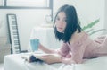 Time for myself. Comfort and relaxation. Pretty young asian woman drinking tea or coffee and reading book while sleeping Royalty Free Stock Photo