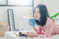 Time for myself. Comfort and relaxation. Pretty young asian woman drinking tea or coffee and reading book while sleeping Royalty Free Stock Photo