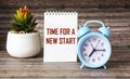 TIME FOR A NEW START text on notepad and wooden background with clock and cactus flower Royalty Free Stock Photo