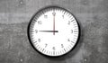 Time at 9 o clock - classic analog clock on rough concrete wall