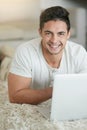 Time off to do just what I want to do. Portrait of a relaxed young man using a laptop on the floor at home. Royalty Free Stock Photo