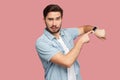 Time is out. Portrait of serious handsome bearded young man in blue casual style shirt standing and looking at camera, pointing on Royalty Free Stock Photo