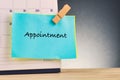 Word APPOINTMENT on blue notepad and calendar on wooden desk over gently lit dark background