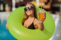 Time for rest on beach! Attractive woman having fun near pool. Wearing black swimwear, holding inflatable ring and cocktail. Royalty Free Stock Photo