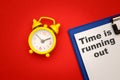 Time is Running Out - phrase on paper with yellow alarm clock aside on red background Royalty Free Stock Photo