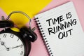 Time is Running Out text written on notepad with alarm clock on pink background Royalty Free Stock Photo
