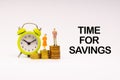 TIME FOR SAVINGS inscription written, alarm clock, coins and businessman miniature