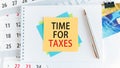 Time for taxes, the text is written on yellow paper lying on a white notepad on the desktop of an office employee, concept