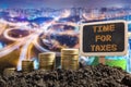 Time for Taxes - Financial opportunity concept. Golden coins in soil Chalkboard on blurred urban background Royalty Free Stock Photo