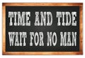 TIME AND TIDE WAIT FOR NO MAN words on black wooden frame school blackboard