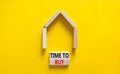 Time to buy house symbol. Concept words `Time to buy` on wooden blocks near miniature house. Beautiful yellow background, copy Royalty Free Stock Photo