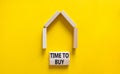 Time to buy house symbol. Concept words `Time to buy` on wooden blocks near miniature house. Beautiful yellow background, copy Royalty Free Stock Photo