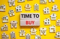 Time to buy house symbol. Concept words `Time to buy` on wooden blocks near miniature houses. Beautiful yellow background, copy Royalty Free Stock Photo