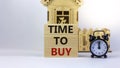 Time to buy real estate. Wooden blocks form the words `time to buy` near miniature house. Black alarm clock. Beautiful white Royalty Free Stock Photo