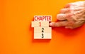 Time to chapter 1 symbol. Concept word Chapter 1 2 3 on wooden block. Businessman hand. Beautiful orange table orange background.