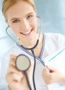 Time to check that heartbeat. Portrait of a pretty nurse holding up a stethoscope while holding a medical file. Royalty Free Stock Photo