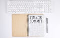 TIME TO COMMIT text on the notebook with keyboard on white background