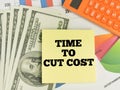 Time to cut cost written on yellow paper note with calculator,money and chart. Royalty Free Stock Photo