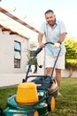 Time to cut the grass. Portrait of a cheerful middle aged man cutting grass with a lawnmower while looking at the camera Royalty Free Stock Photo