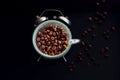 Time to drink coffee: coffee beans in a cup in the form of an alarm clock on a dark background, beans scattered nearby, top view, Royalty Free Stock Photo