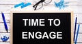 TIME TO ENGAGE written on a black note-board next to blue paper clips, pencils and a pen Royalty Free Stock Photo