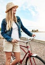 Time to go out exploring. a cheerful young woman wearing a hat and getting ready to ride her bicycle while looking out