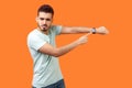 Time to go! Portrait of displeased impatient brunette man pointing at wristwatches. on orange background