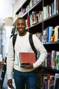 Time to hit the books. Portrait of a happy young man carrying books in a library at college. Royalty Free Stock Photo